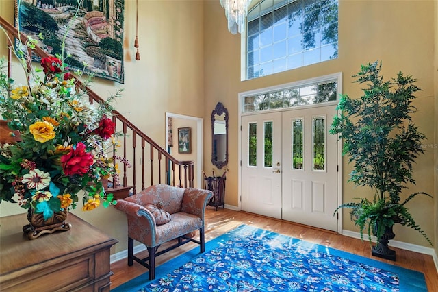 foyer with an inviting chandelier, light hardwood / wood-style floors, and a high ceiling