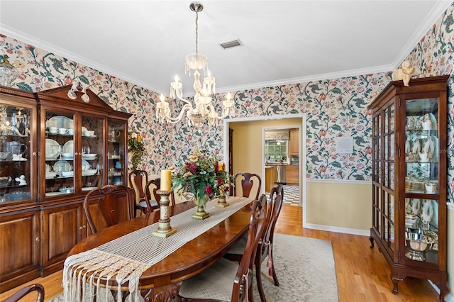 dining area featuring an inviting chandelier, crown molding, and light hardwood / wood-style floors