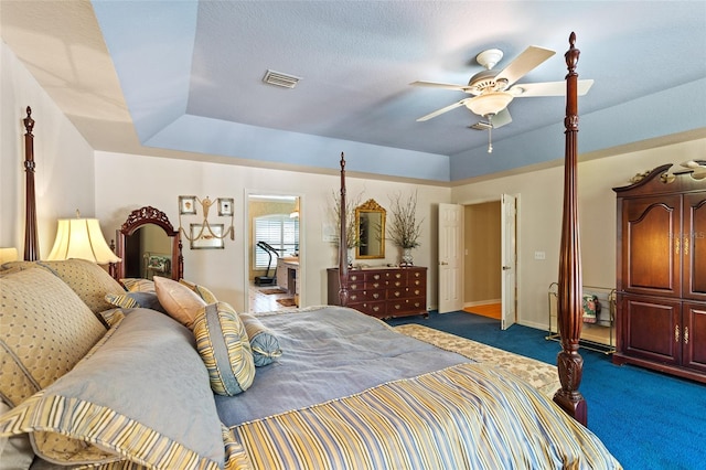 bedroom with a tray ceiling, dark carpet, and ceiling fan