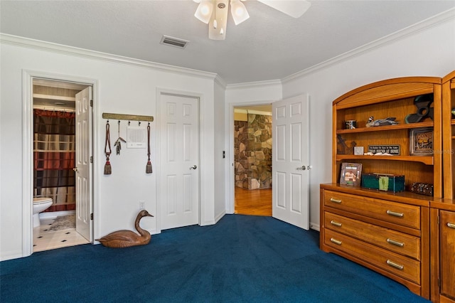 bedroom featuring a closet, ceiling fan, dark carpet, ensuite bath, and ornamental molding