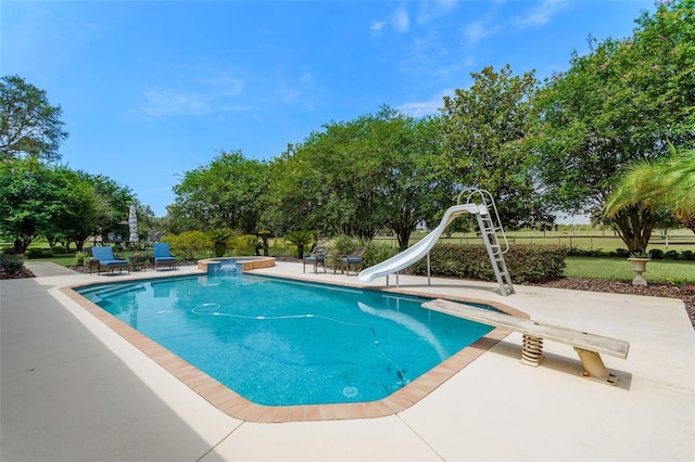 view of pool featuring a water slide, a patio area, and a diving board