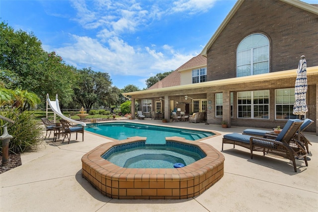 view of pool featuring a water slide, a patio area, and an in ground hot tub