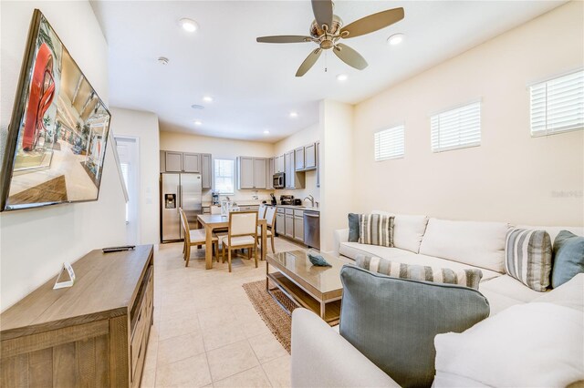 living room featuring light tile floors, ceiling fan, and sink