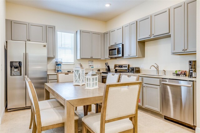 kitchen featuring light tile floors, a kitchen island, appliances with stainless steel finishes, and sink