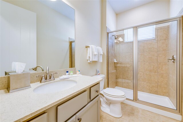 bathroom with toilet, a shower with door, vanity with extensive cabinet space, and tile flooring