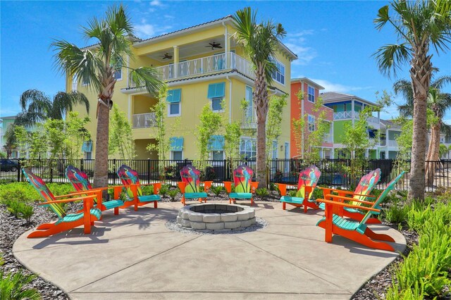 view of patio with a balcony, ceiling fan, and an outdoor fire pit