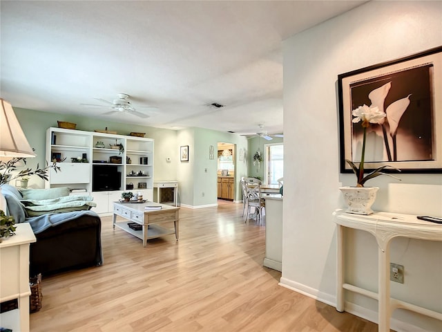 living room with ceiling fan and light hardwood / wood-style flooring