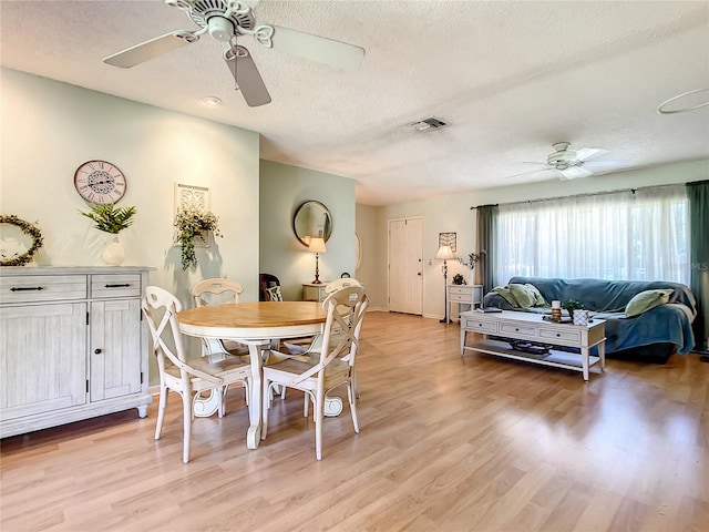 dining area with a textured ceiling, light hardwood / wood-style floors, and ceiling fan