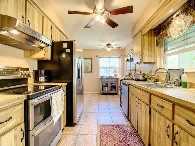 kitchen featuring ceiling fan, light tile floors, sink, appliances with stainless steel finishes, and a textured ceiling