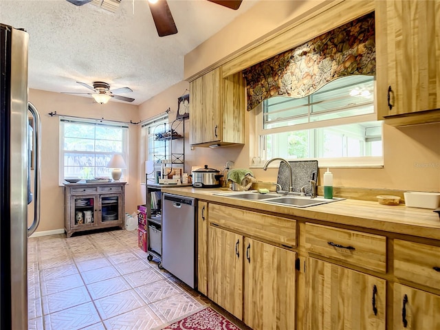 kitchen featuring a textured ceiling, ceiling fan, a healthy amount of sunlight, and stainless steel appliances