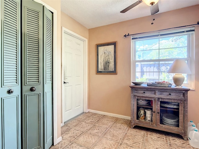 interior space with light tile floors, ceiling fan, and a textured ceiling