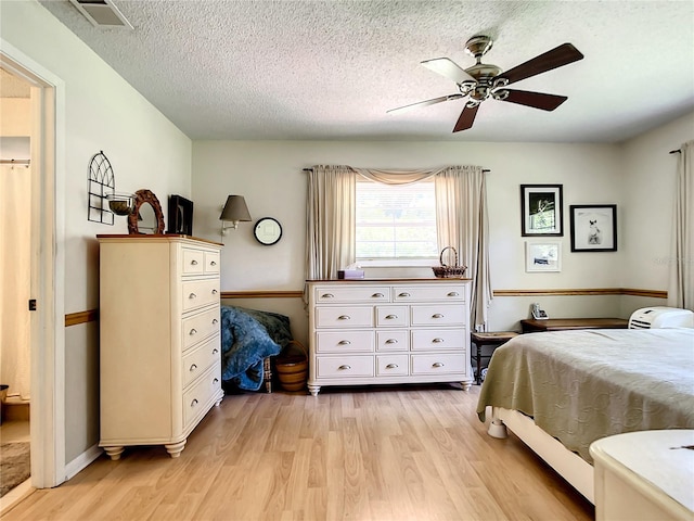 bedroom with a textured ceiling, ceiling fan, and light wood-type flooring