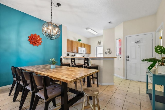 dining space with an inviting chandelier, a textured ceiling, and light tile floors