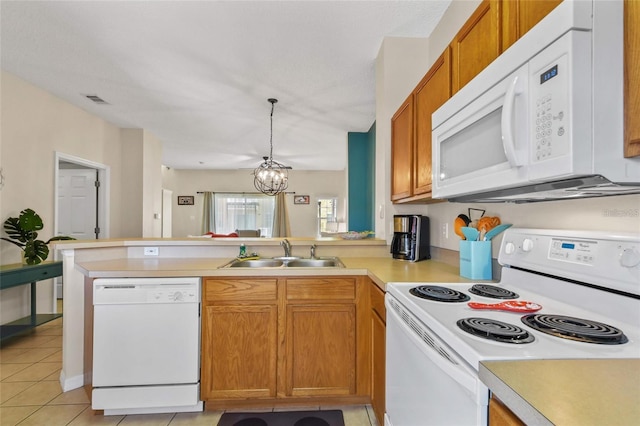 kitchen featuring kitchen peninsula, white appliances, sink, light tile floors, and a chandelier