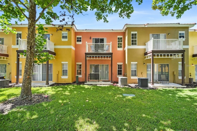 rear view of house with a balcony, a lawn, and central AC unit