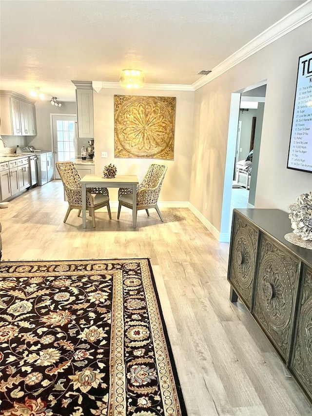 dining area with ornamental molding and light wood-type flooring