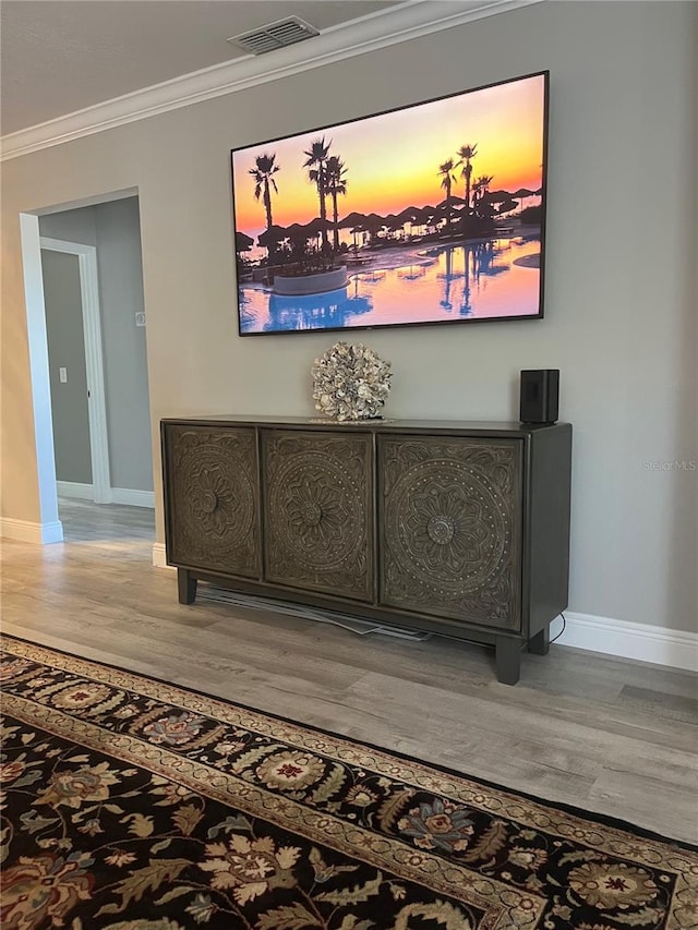 interior details with ornamental molding and hardwood / wood-style flooring