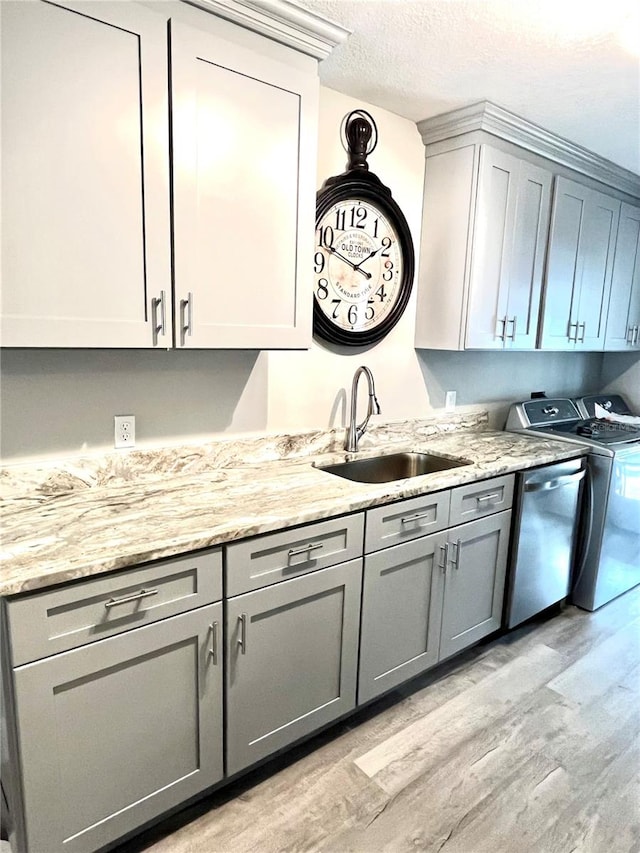 kitchen with sink, light stone counters, gray cabinetry, light hardwood / wood-style flooring, and separate washer and dryer