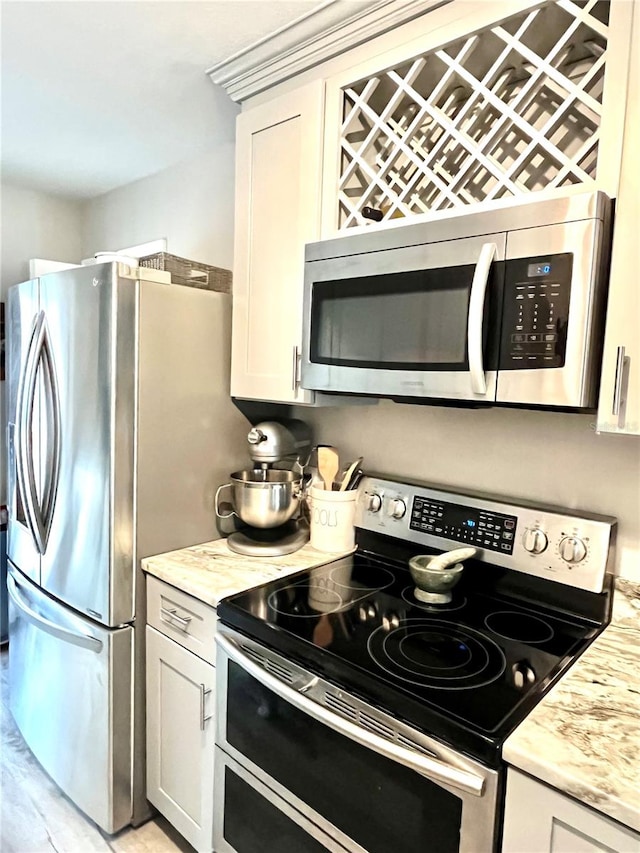 kitchen featuring white cabinets, appliances with stainless steel finishes, and light stone counters