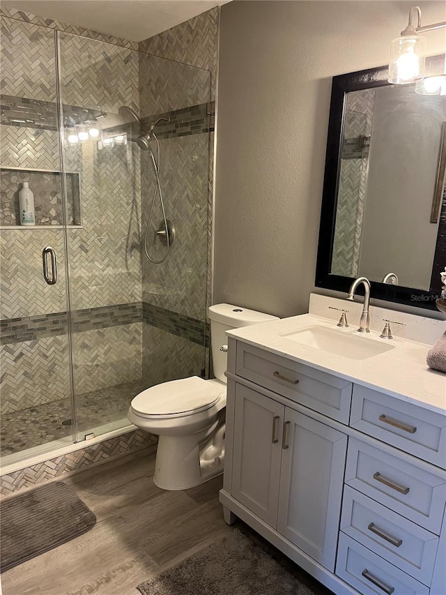 bathroom featuring an enclosed shower, toilet, vanity, and wood-type flooring