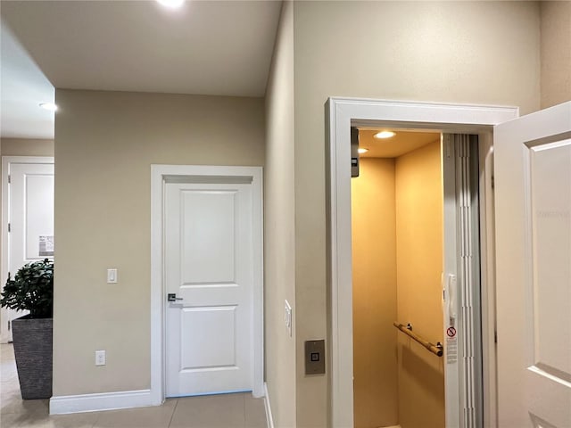 hallway with light tile flooring and elevator