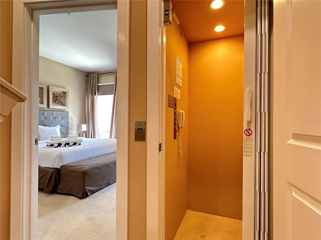 hallway featuring light colored carpet and elevator