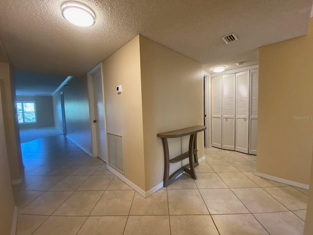 corridor with a textured ceiling and light tile patterned floors