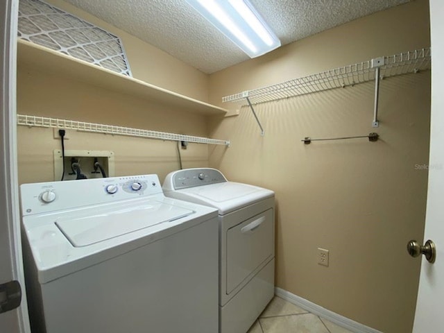 laundry room featuring independent washer and dryer, a textured ceiling, and light tile patterned floors