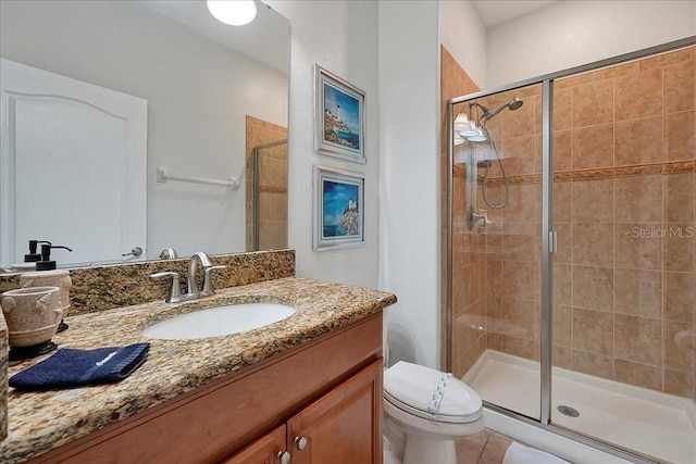 bathroom featuring toilet, tile floors, a shower with shower door, and oversized vanity