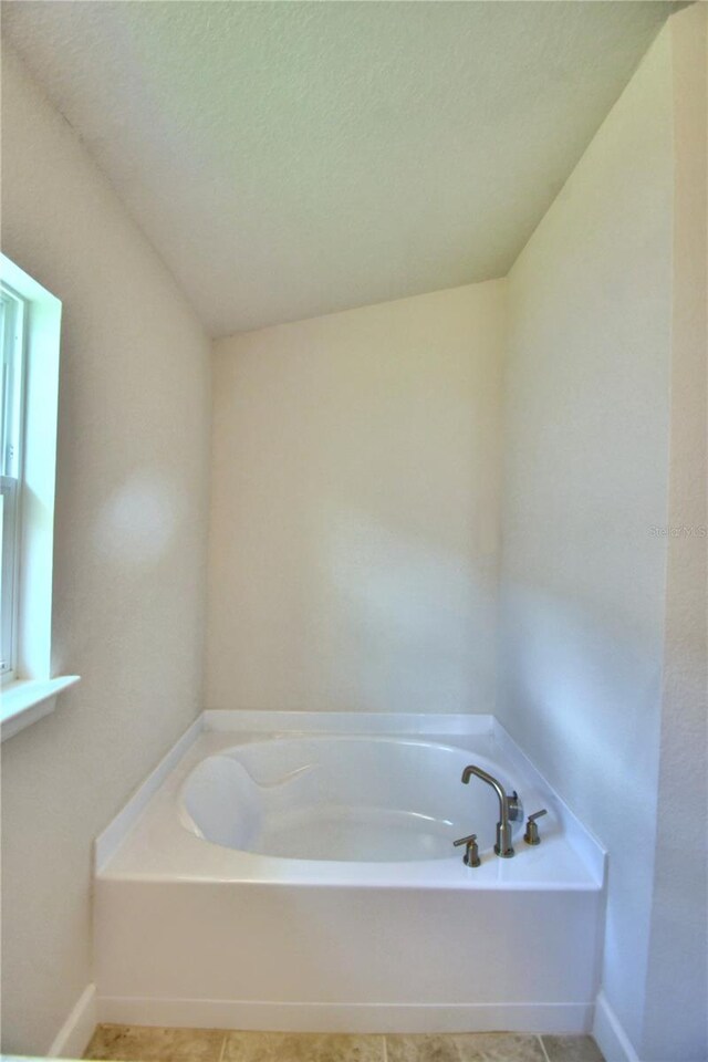 bathroom with a tub, a textured ceiling, and tile patterned flooring