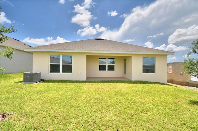 rear view of property featuring central air condition unit and a lawn