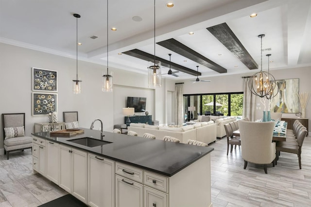 kitchen with pendant lighting, an island with sink, white cabinets, sink, and ceiling fan with notable chandelier