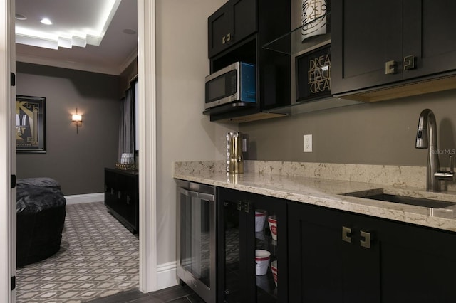 kitchen featuring light stone countertops, wine cooler, sink, and crown molding