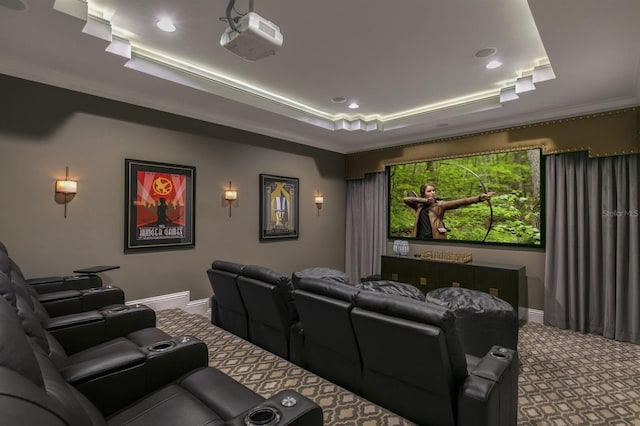 cinema room with ornamental molding, a tray ceiling, and carpet flooring