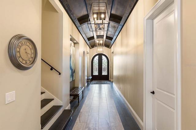 doorway to outside featuring french doors, dark tile patterned flooring, and a chandelier