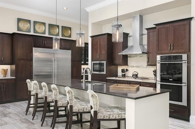 kitchen featuring a breakfast bar, a kitchen island with sink, sink, wall chimney range hood, and appliances with stainless steel finishes