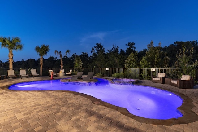 pool at night with a patio and pool water feature