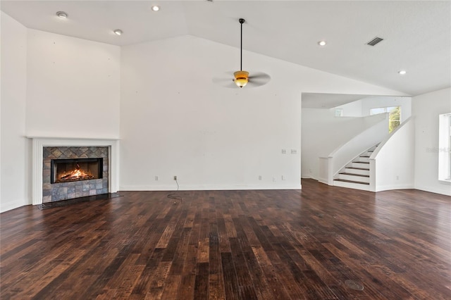 unfurnished living room with a tiled fireplace, ceiling fan, high vaulted ceiling, and dark wood-type flooring