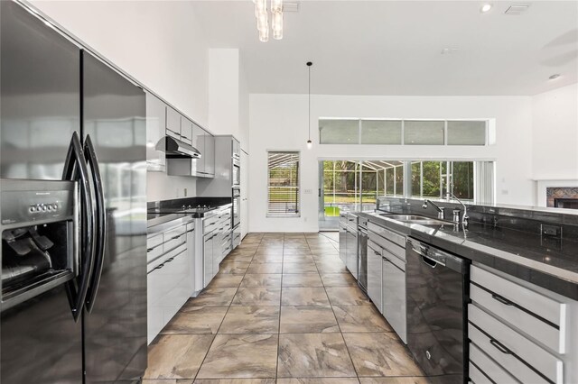 kitchen with light tile floors, refrigerator with ice dispenser, hanging light fixtures, dishwasher, and sink