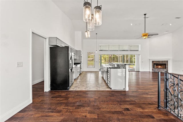 kitchen with black refrigerator with ice dispenser, tile flooring, high vaulted ceiling, and ceiling fan with notable chandelier