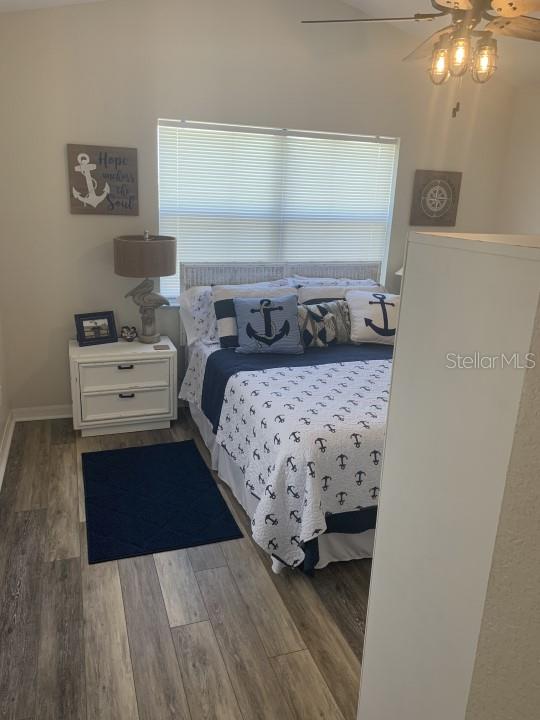 bedroom featuring ceiling fan, multiple windows, and dark hardwood / wood-style flooring