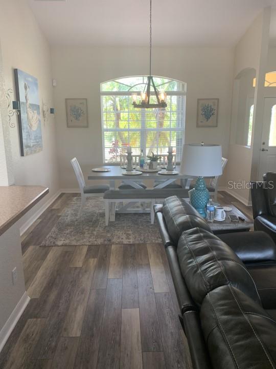 dining room featuring a notable chandelier, lofted ceiling, and dark wood-type flooring