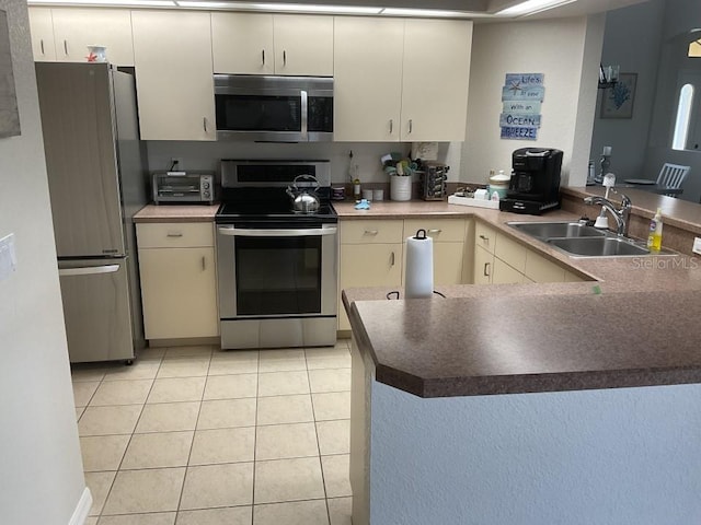 kitchen featuring light tile floors, appliances with stainless steel finishes, kitchen peninsula, and sink