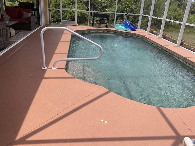 view of pool with glass enclosure and a patio