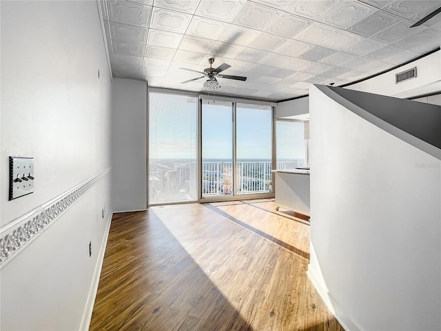 unfurnished room featuring ceiling fan, a wall of windows, and wood-type flooring