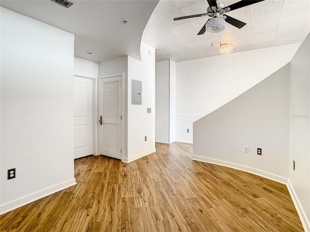 unfurnished room with ceiling fan, electric panel, and light wood-type flooring