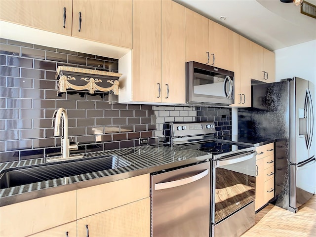 kitchen with appliances with stainless steel finishes, sink, light brown cabinetry, and decorative backsplash