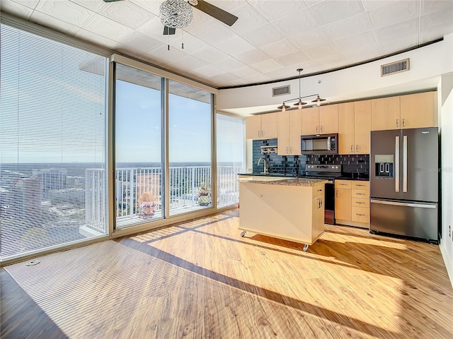 kitchen featuring tasteful backsplash, stainless steel appliances, hanging light fixtures, and light wood-type flooring