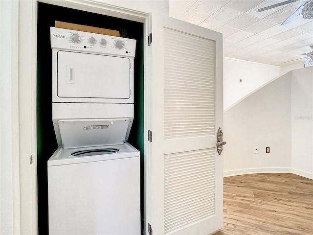 laundry room featuring light wood-type flooring and stacked washing maching and dryer