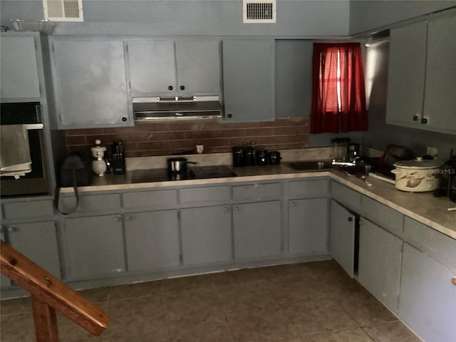 kitchen featuring backsplash, light tile floors, sink, and black electric stovetop